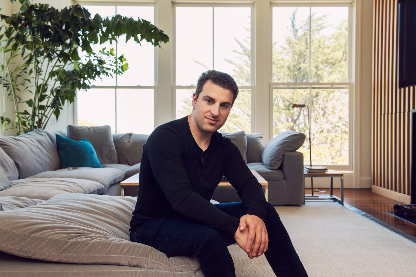 Airbnb CEO Brian Chesky poses inside a living room.