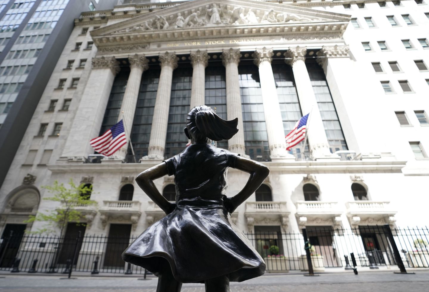 Fearless Girl, a bronze sculpture by Kristen Visbalthe, with a PPE mask on in front of the New York Stock Exchange in the Wall Street Financial District of Manhattan New York May 19, 2020.