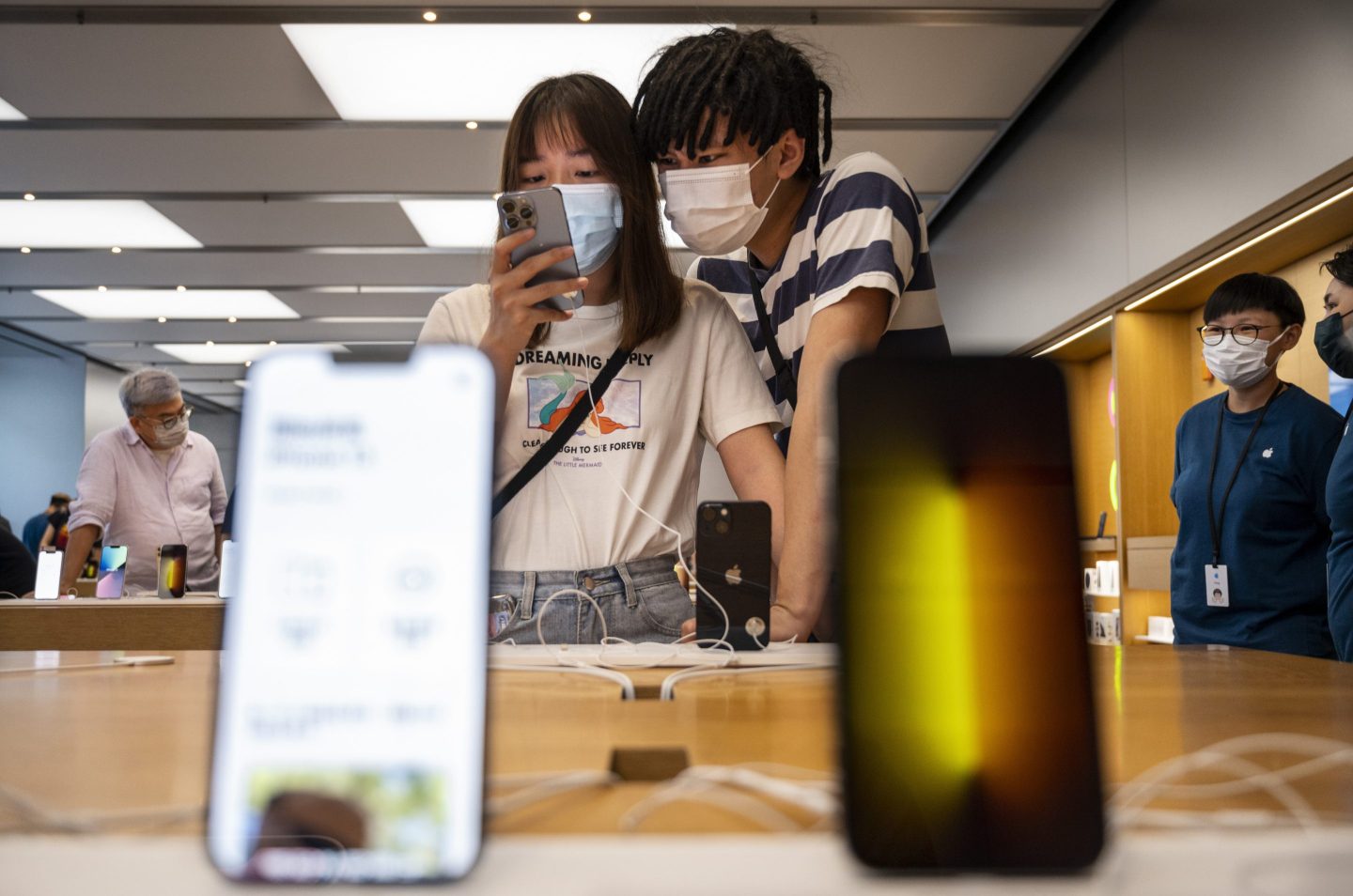 a man and a woman looking at an iPhone in a store