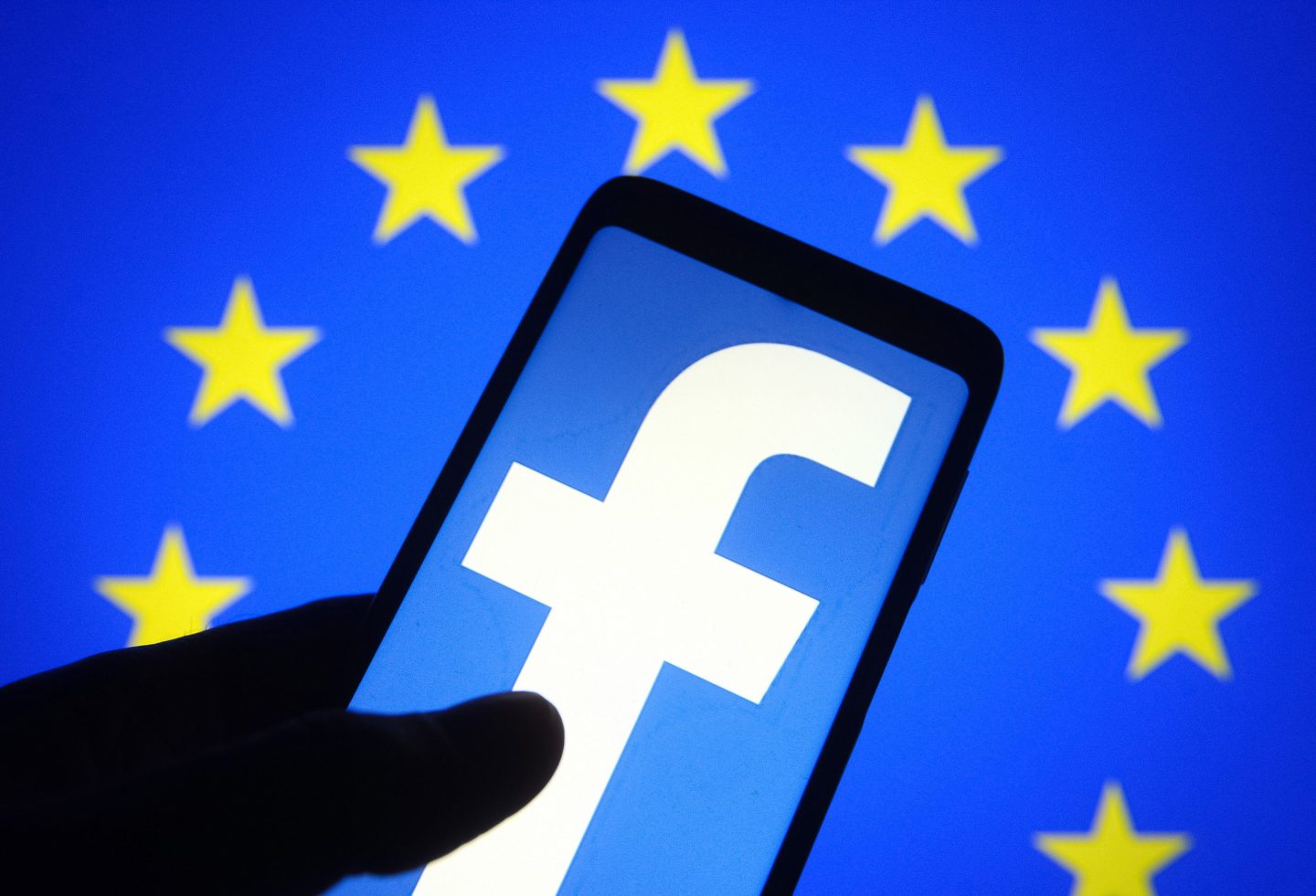 In this photo illustration, Facebook logo seen displayed on a smartphone screen and the European Union (EU) flag in the background.