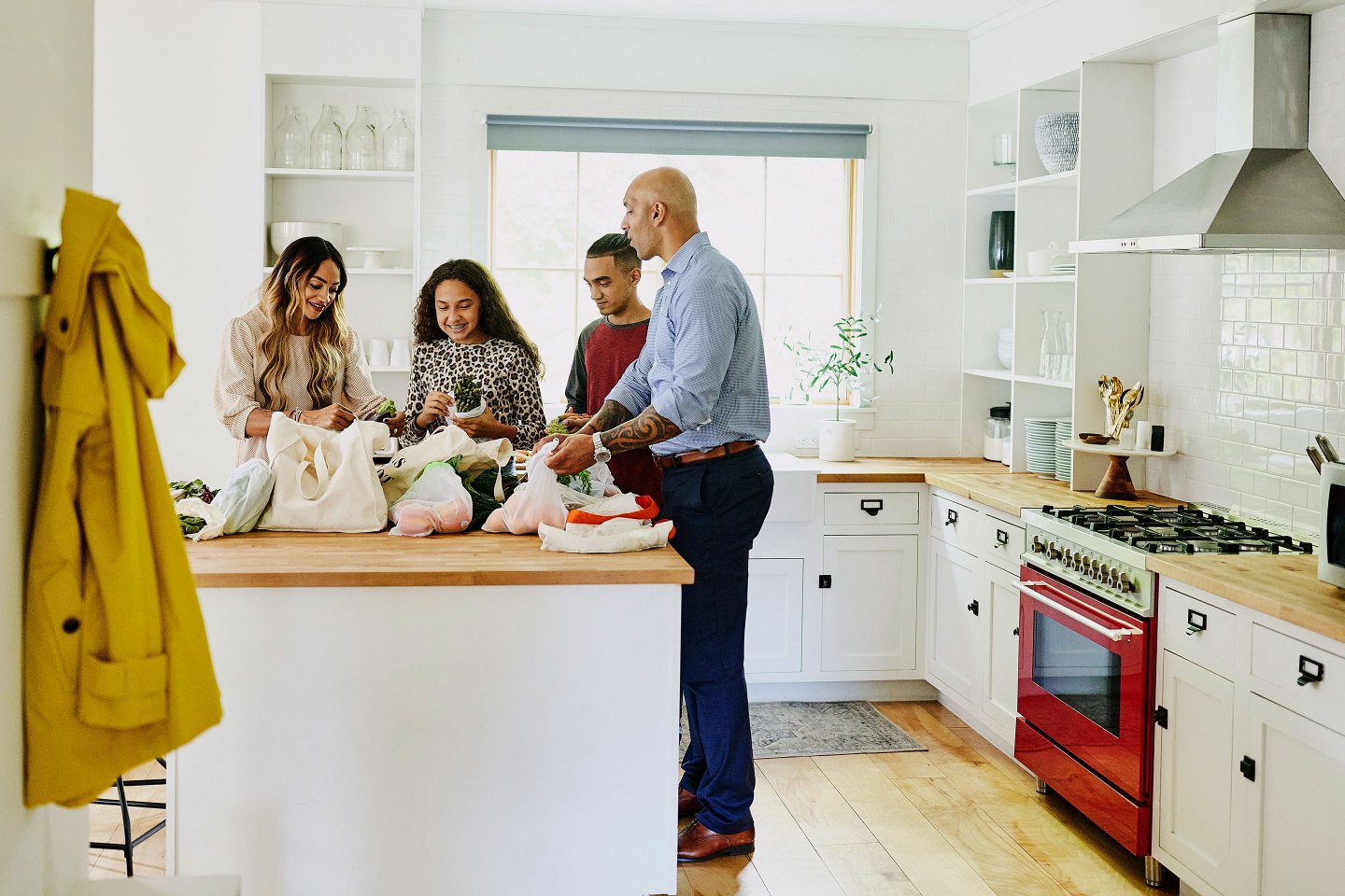Wide shot of family unloading groceries in kitchen after shopping