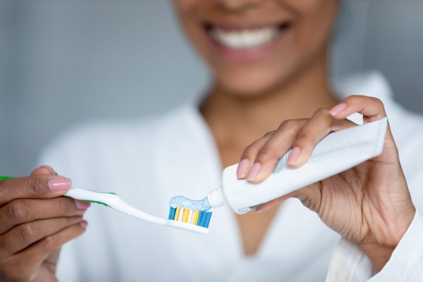 Woman is smiling as she prepares to brush her teeth