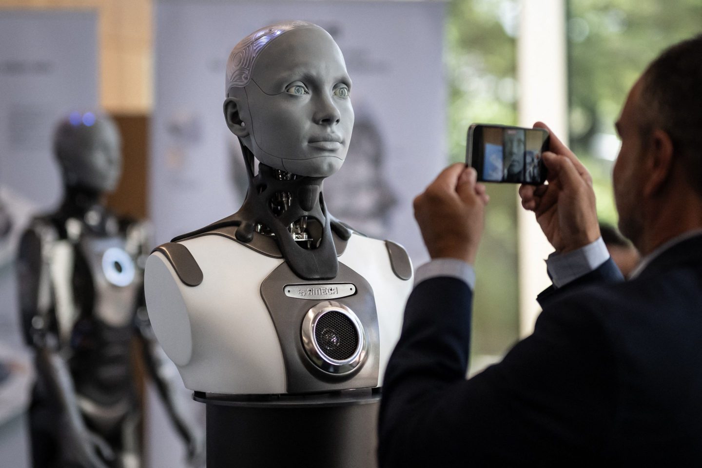 A visitor takes a picture of humanoid AI robot "Ameca" at the booth of Engineered Arts company during the world's largest gathering of humanoid AI Robots as part of International Telecommunication Union (ITU) AI for Good Global Summit in Geneva, on July 5, 2023.