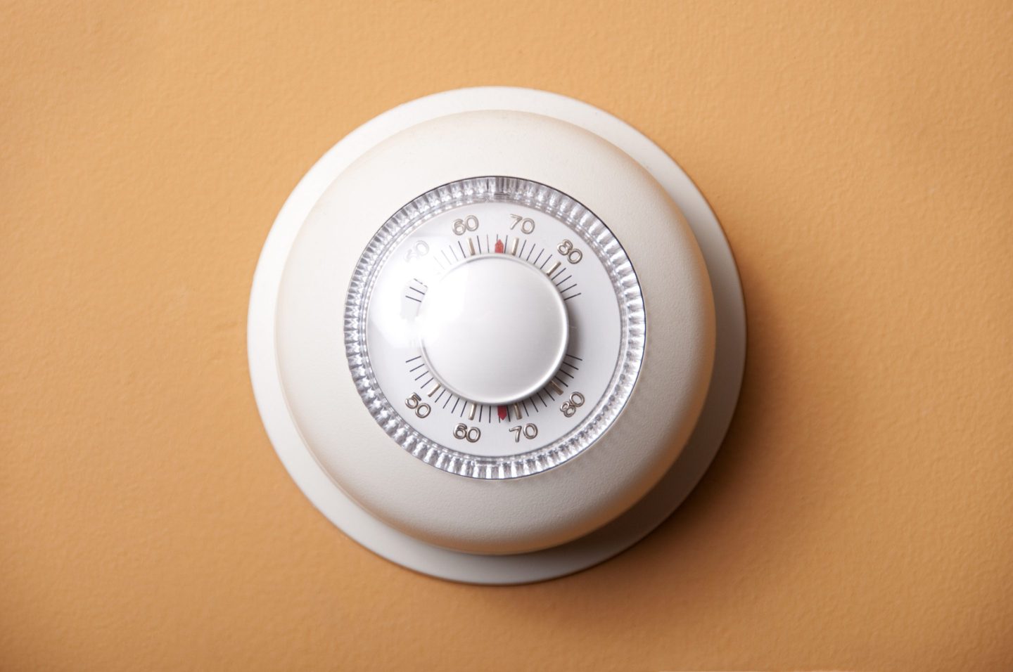 round thermostat on orange wall