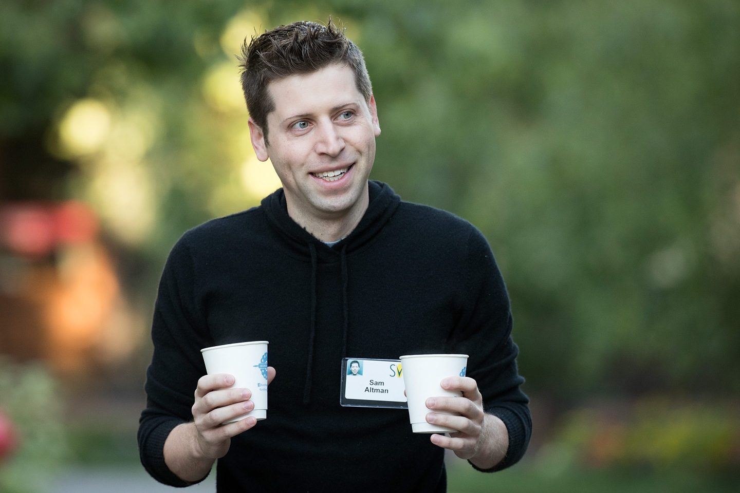 OpenAI founder and CEO Sam Altman holding two paper cups.