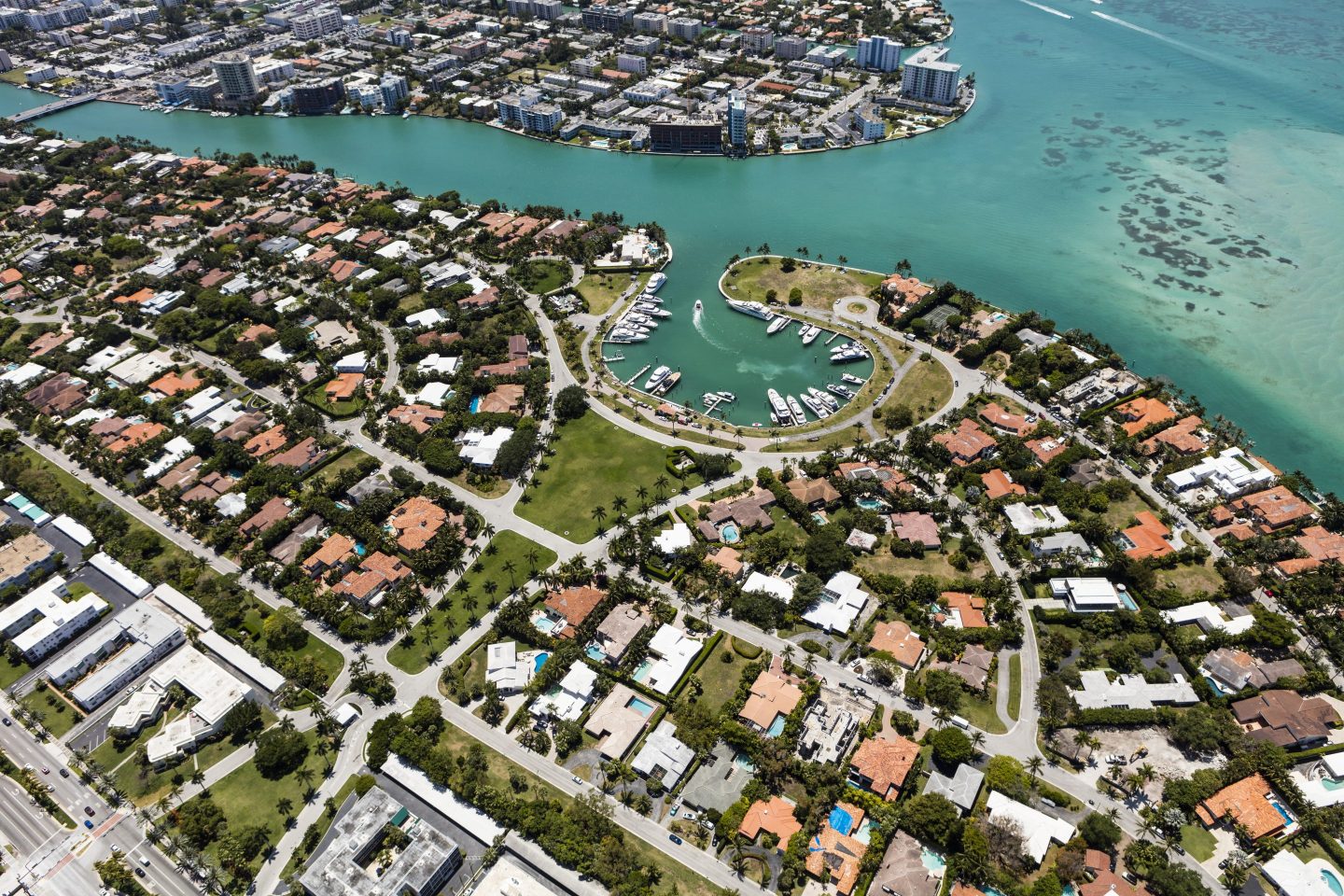 Aerial view of houses, hotels, buildings, boats, marina, and Indian Creek in South Beach Miami