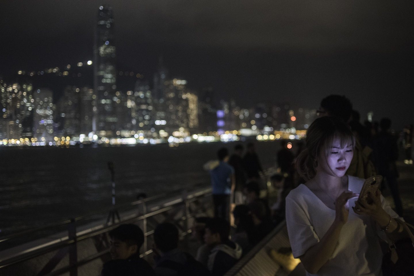 A woman looks at a mobile phone after the skyline buildings lights were switched off for the Earth Hour environmental campaign in Hong Kong on March 24, 2018. / AFP PHOTO / Philip FONG (Photo credit should read PHILIP FONG/AFP via Getty Images)
