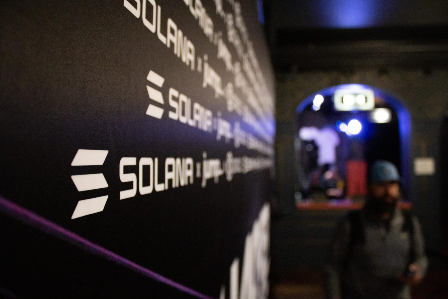 A man passes by a poster that says Solana.